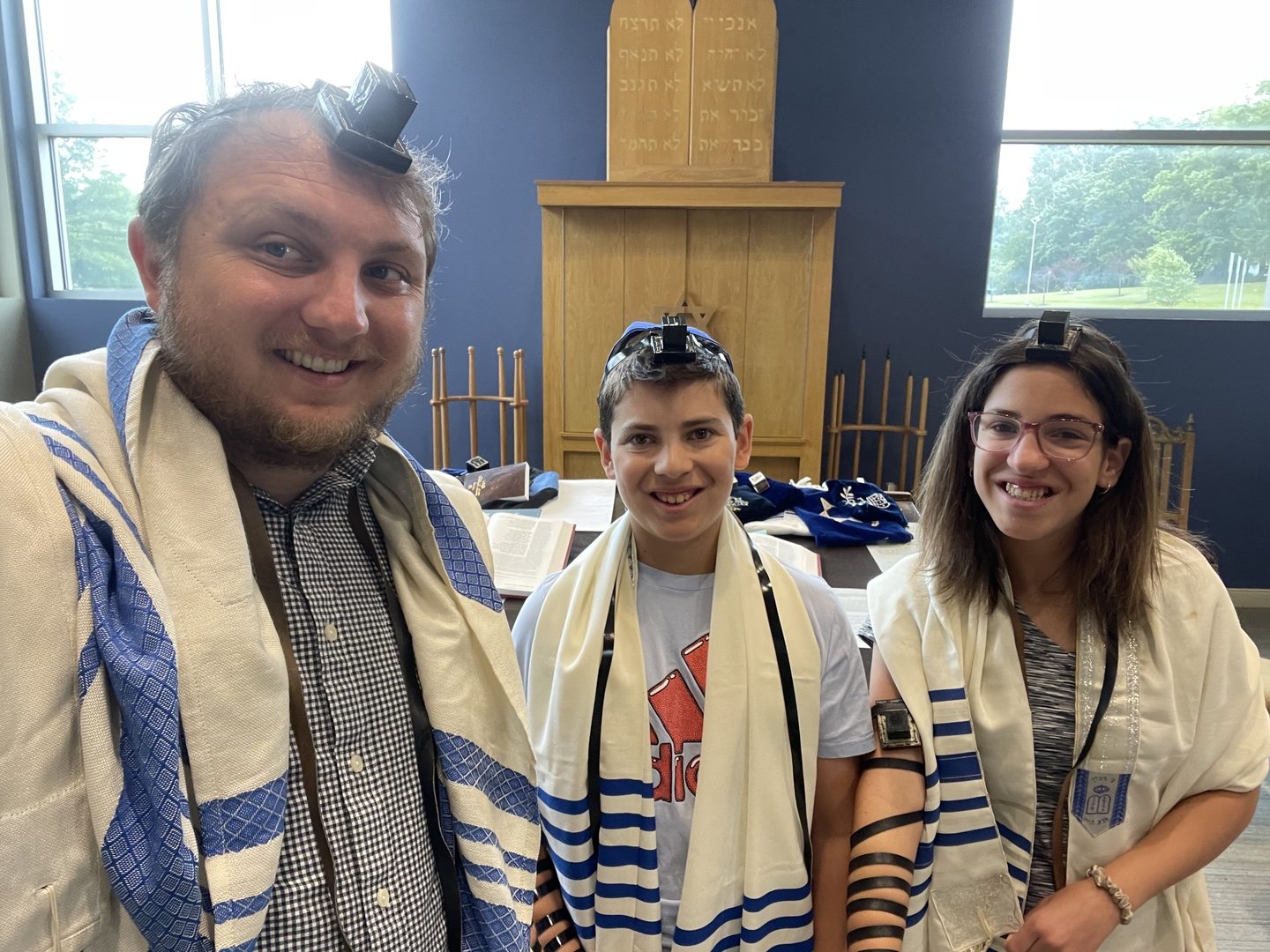 Rabbi Micah Friedman with two b'nei mitzvah students wearing tallit and tefillin.