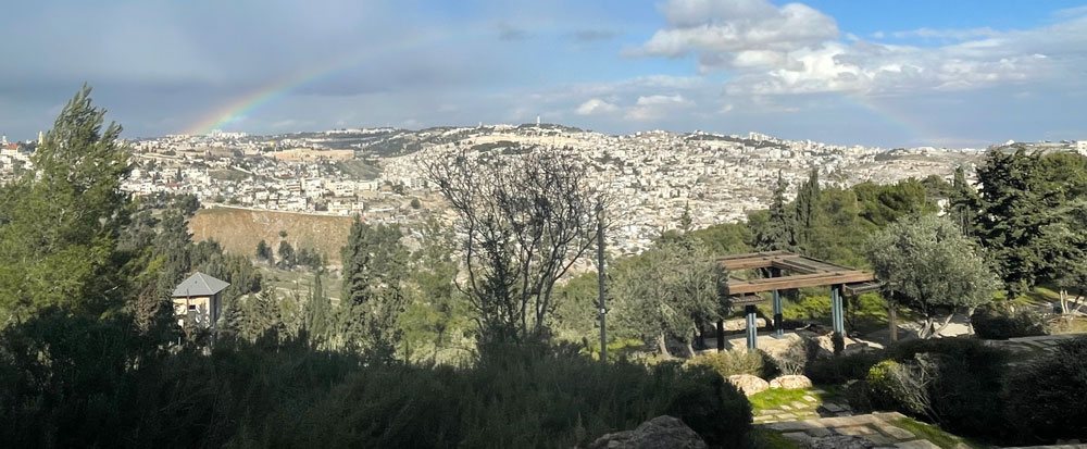 A rainbow stretching across a Jerusalem landscape.